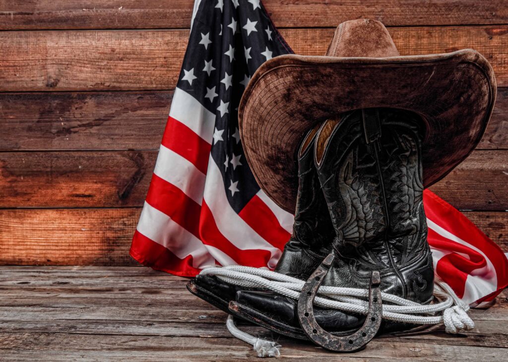 Wrangler National Finals Rodeo in Las Vegas Shabby old ornate classic cowboy boots hat and lasso on wooden background and USA flag background